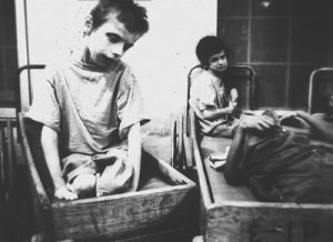 Children waiting, sitting in wooden boxes, circa 1960