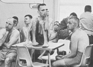 Poorly clothed residents gather in the day room of an institution, circa 1960s